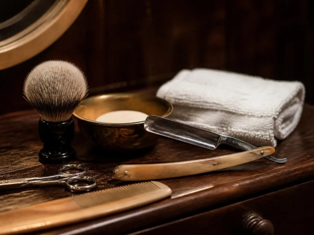 Blaireau, rasoir coupe-chou, bol de savon et serviette sur un comptoir en bois
